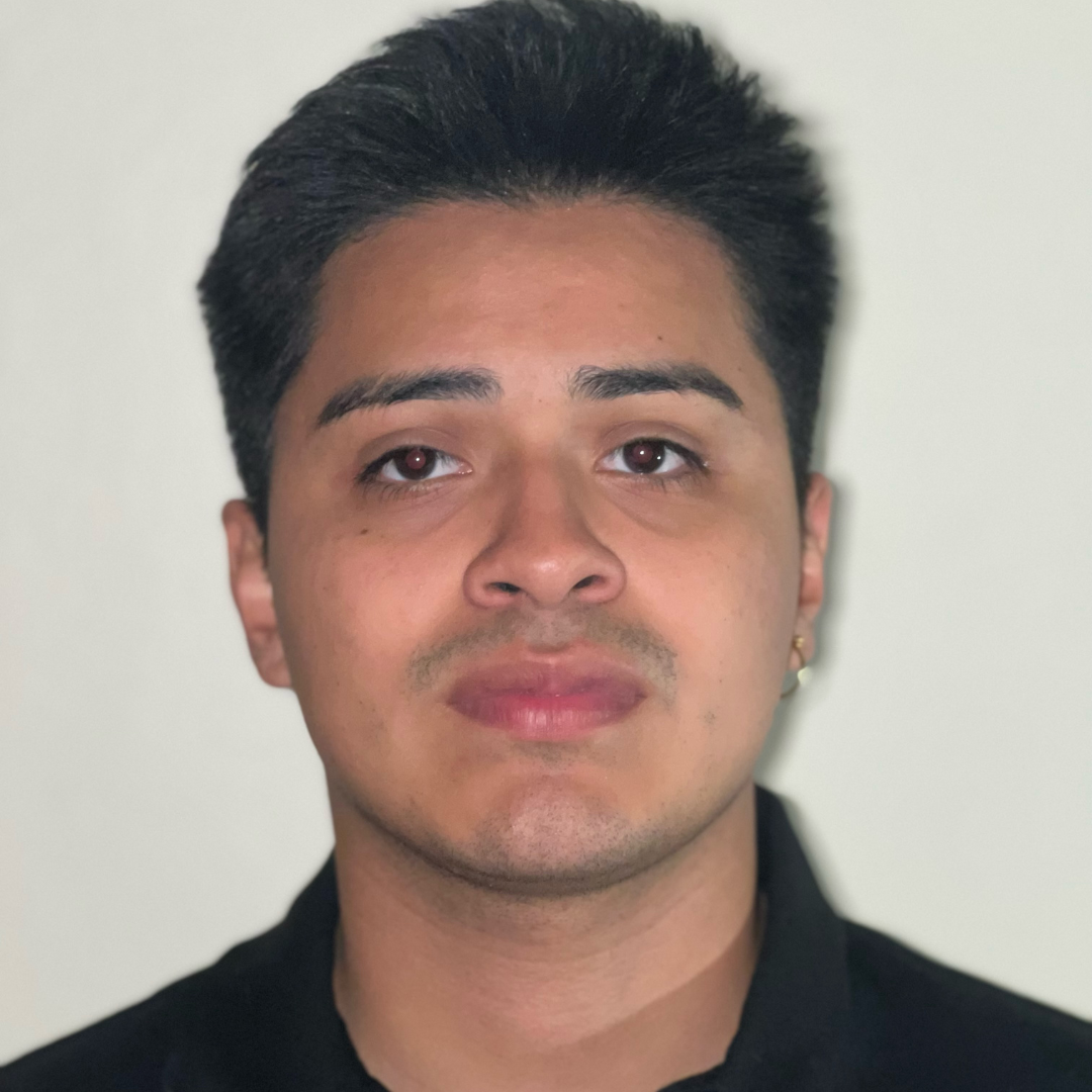 young man standing in front of white wall in black button down