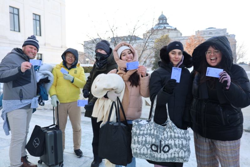 group of students posing with tickets in the snow