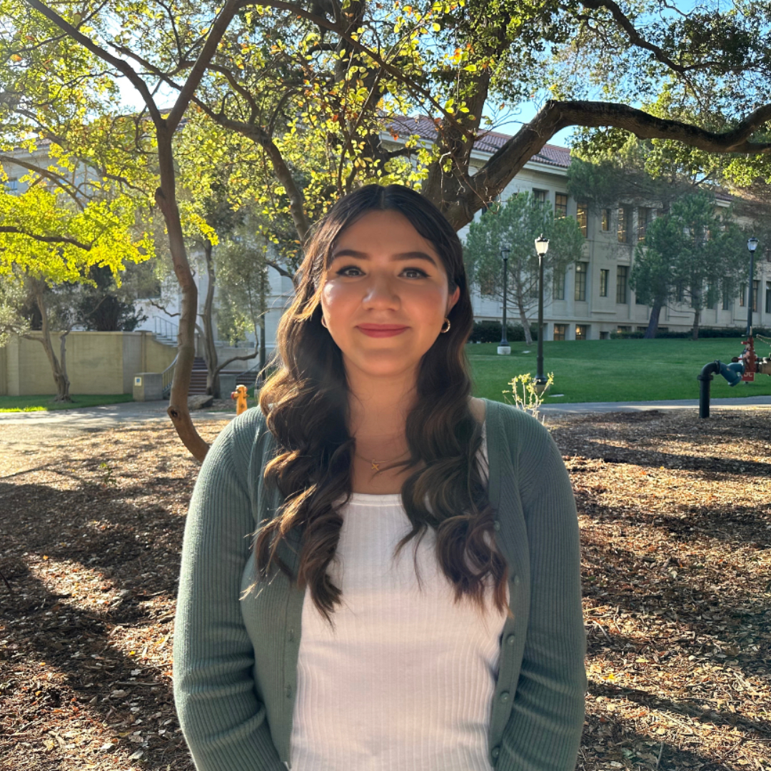 young woman in front of tree on Berkeley campus in white shirt and green cardigan