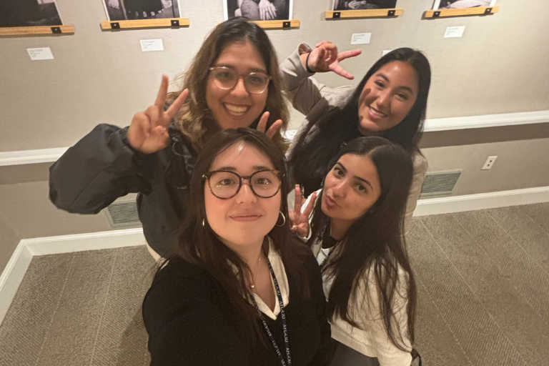group of young women taking a selfie in front of pictures