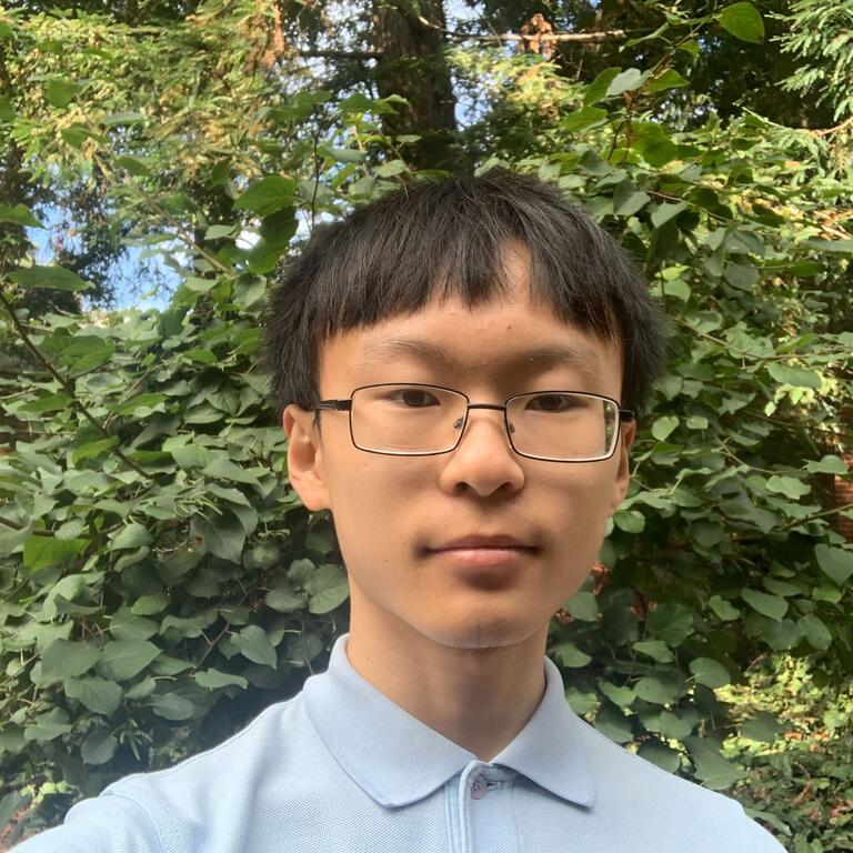 young boy with black hair wearing glasses and light blue polo shirt