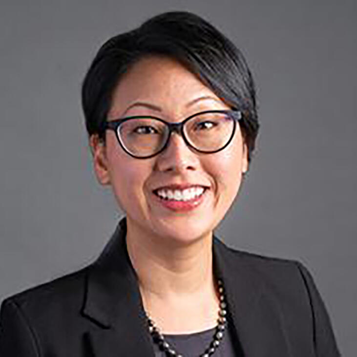 Paulette Cha, smiling in a black blazer against a gray background