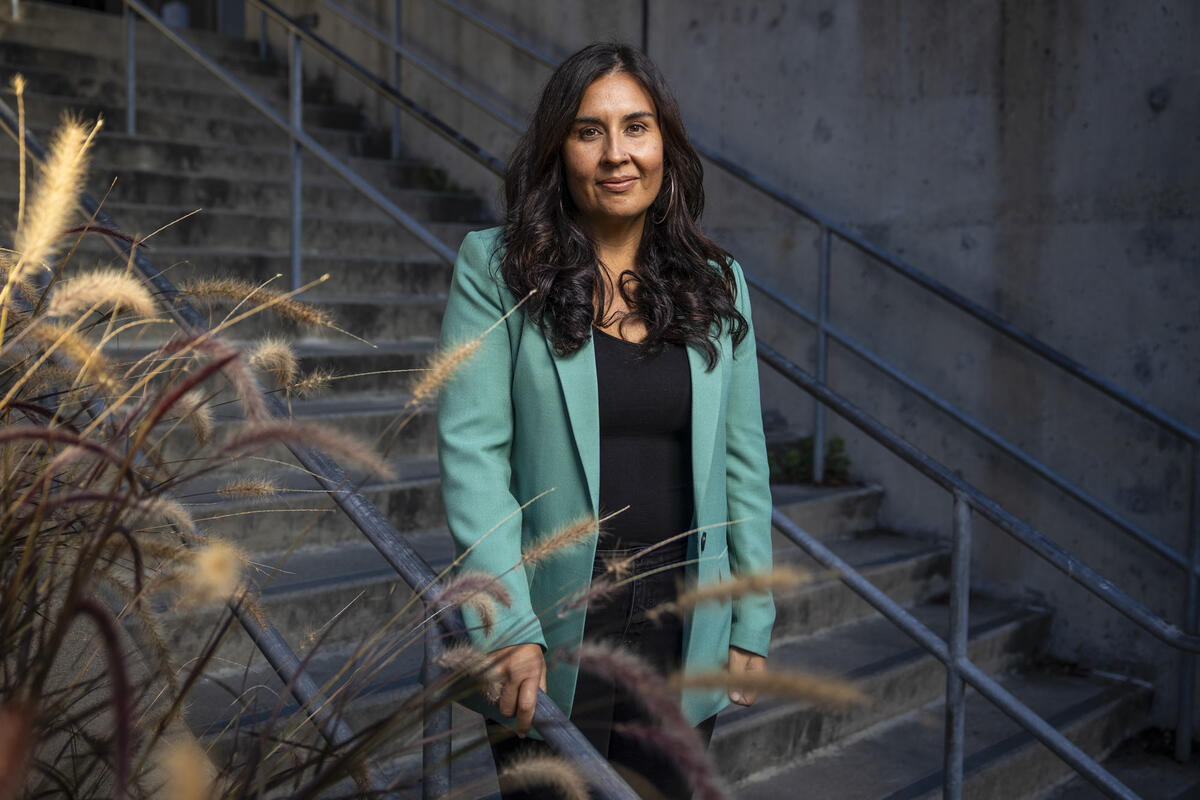 IGS Co-Director Cristina Mora standing on outdoor steps wearing a teal blazer, black shirt, and pants