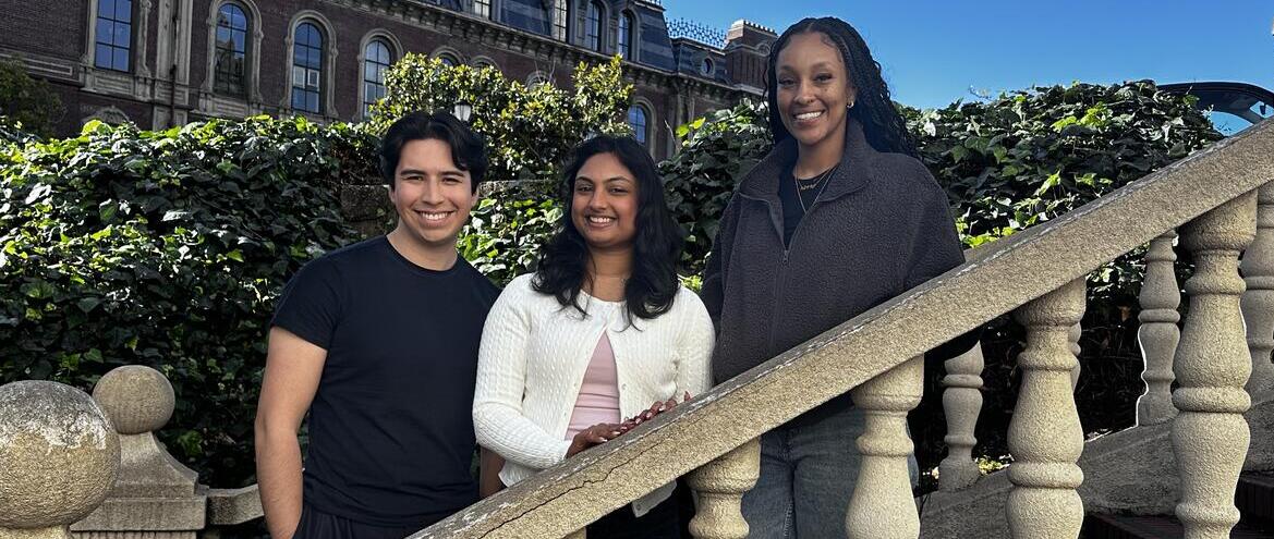 Undergraduate young Latino man, young South Asian woman, young African-American woman standing outside on stairs at UC Berkeley