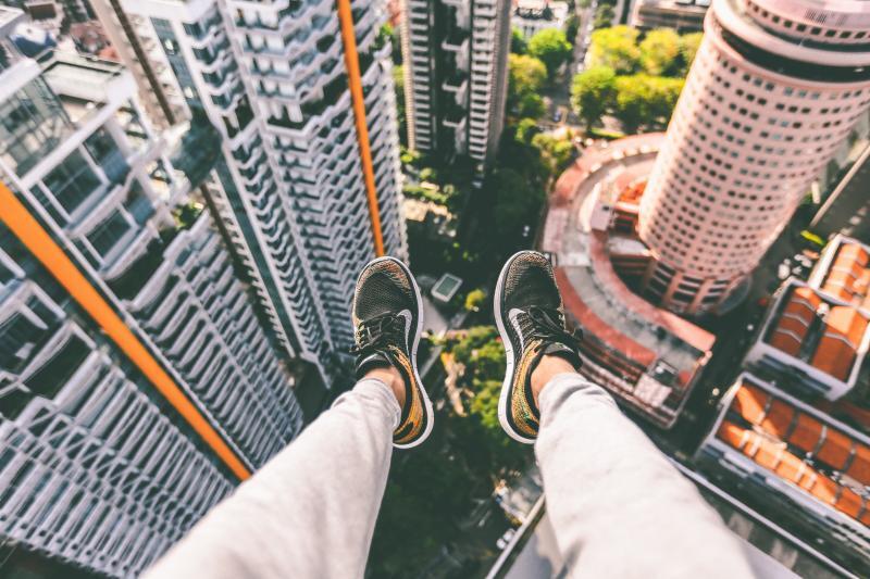 dangling feet sitting on top of a tall building looking at the bottom view