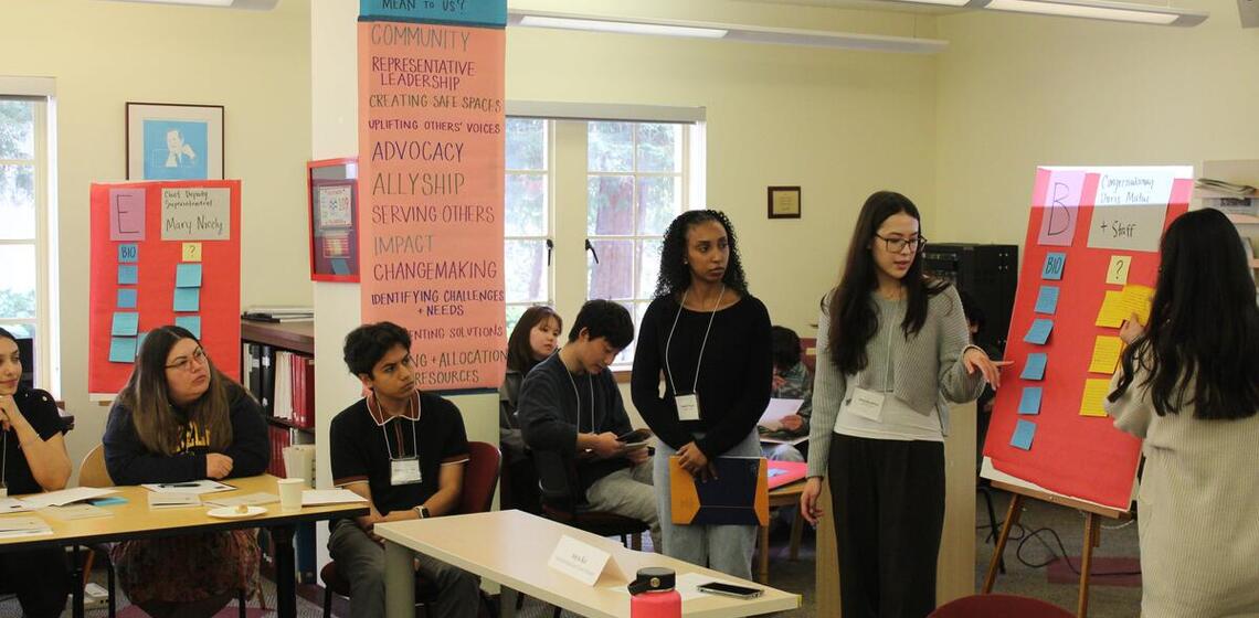 Young people present their notes to a room full of people