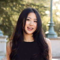 young woman UC Berkeley graduate with straight dark brown hair standing outside wearing a black shirt 