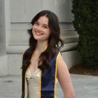 young woman UC Berkeley graduate with wavy brown hair and graduation stole