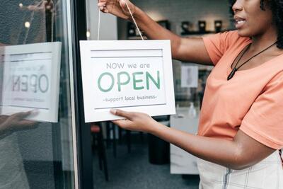 person holding up an "open" sign