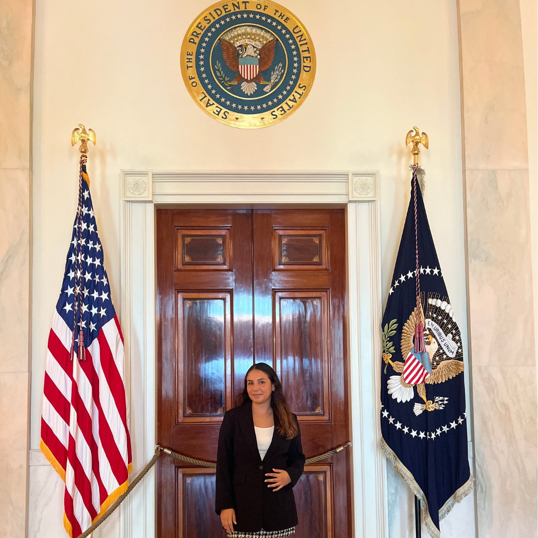 Photo of UCDC Fellow taken in The White House under the presidential seal and alongside the American flag.